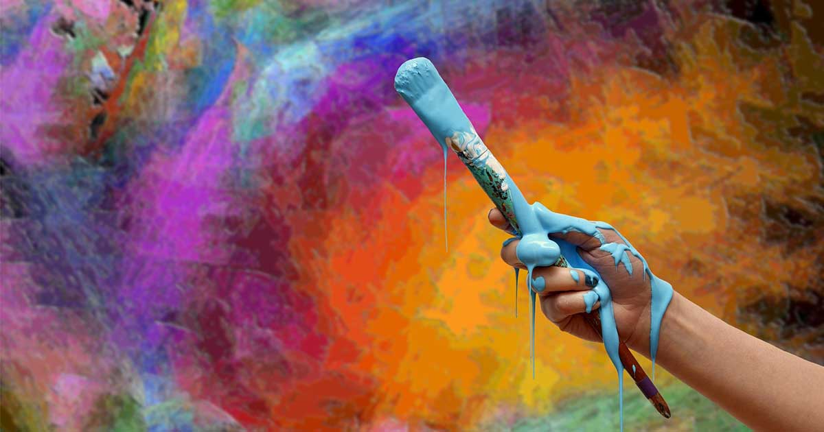 Bunt bemalter Hintergrund, Hand mit Pinsel von dem hellblaue Farbe tropft im Vordergrund.